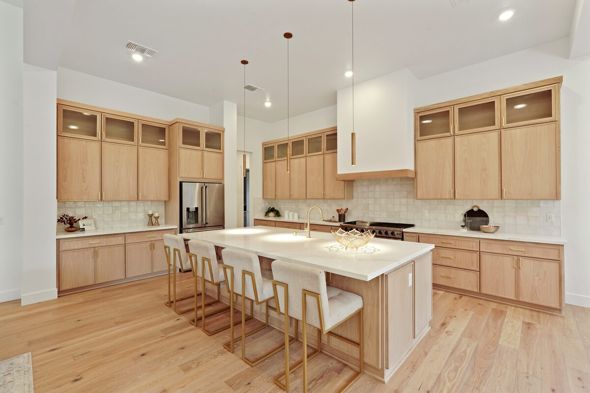Chef's kitchen with waterfall quartz island and natural wood cabinetry