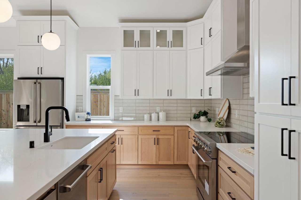 Kitchen with white shaker cabinets, natural wood island and quartz countertops